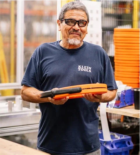 Klein Tools worker in a plant holding a wire pulling dispenser